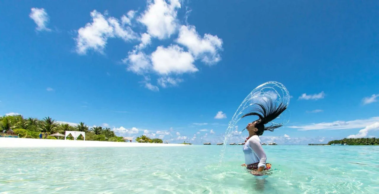 beach and clear water with woman swishing wet hair