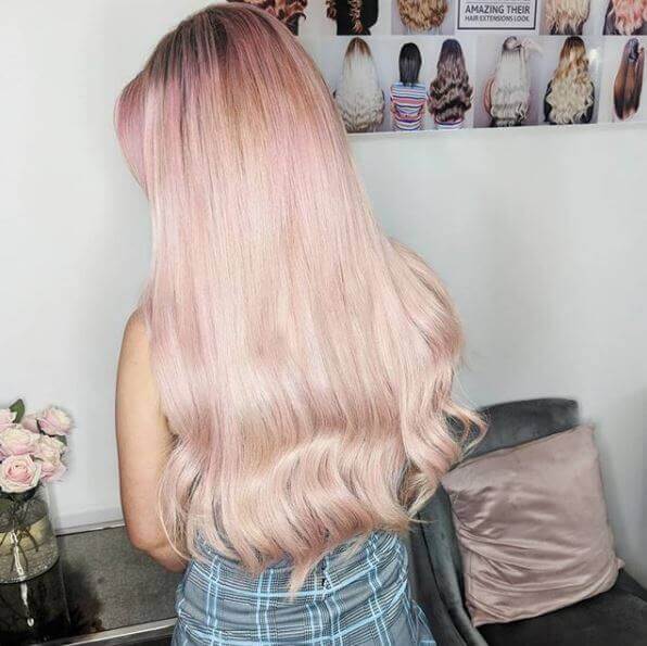 long rose gold wavy hair extensions on client